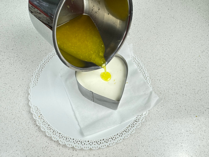 Versa gelatina al limone nello stampo a cuore sopra alla cheesecake